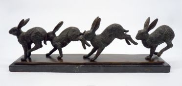 'Four hares running', a heavy bronze mantle piece ornament on marble effect plinth,