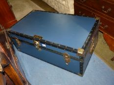 A travel trunk in dark blue with studded borders and metal corners,