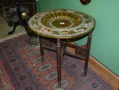 A Benares style table in brass and copper on folding wood base,