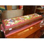 A long Victorian kneeler with floral pattern tapestry cover in red, white, green and blue, 43" long.