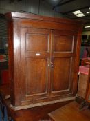 A wall hanging dark Oak corner Cupboard of traditional Georgian design with a pair of opposing