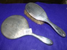 A silver backed mirror, Birmingham hallmarks rubbed, together with a silver backed hairbrush,