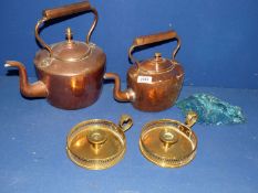 Two copper kettles and a pair of chambersticks.