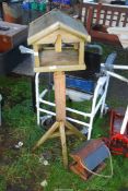A wooden bird table and hanging feeder.