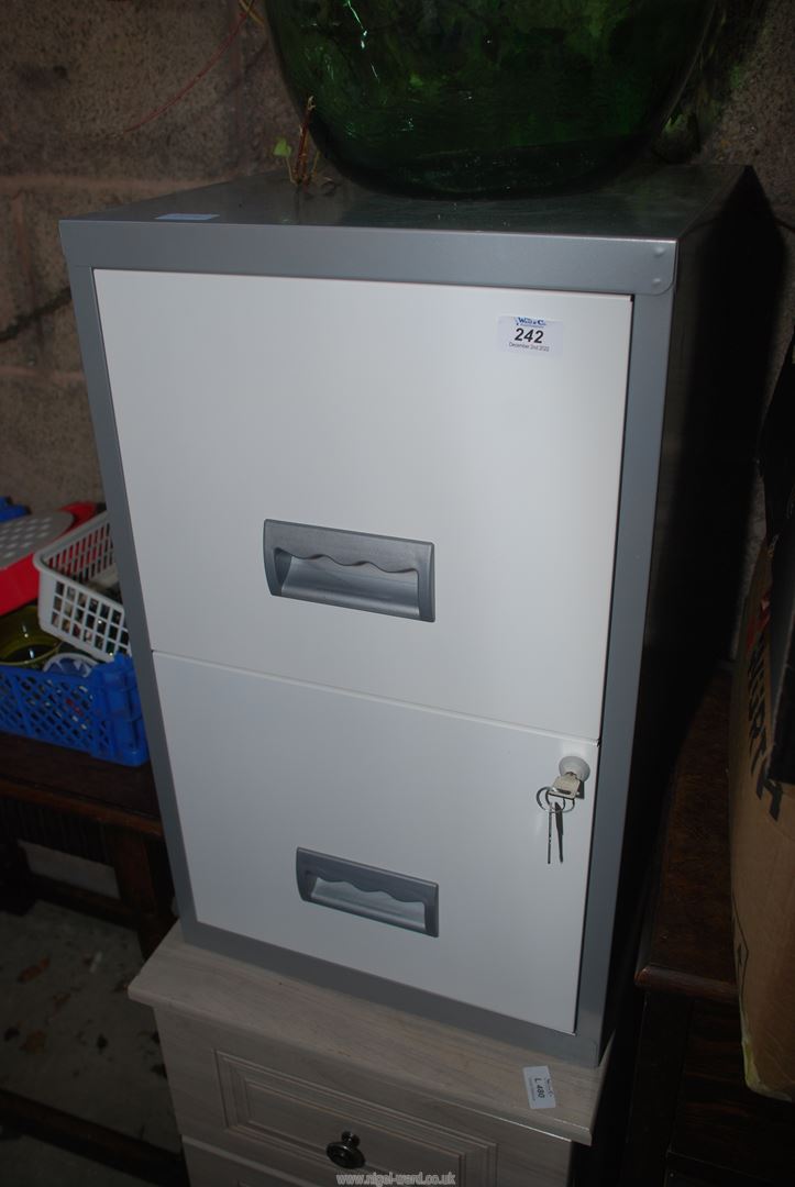 A metal two drawer filing cabinet with keys.