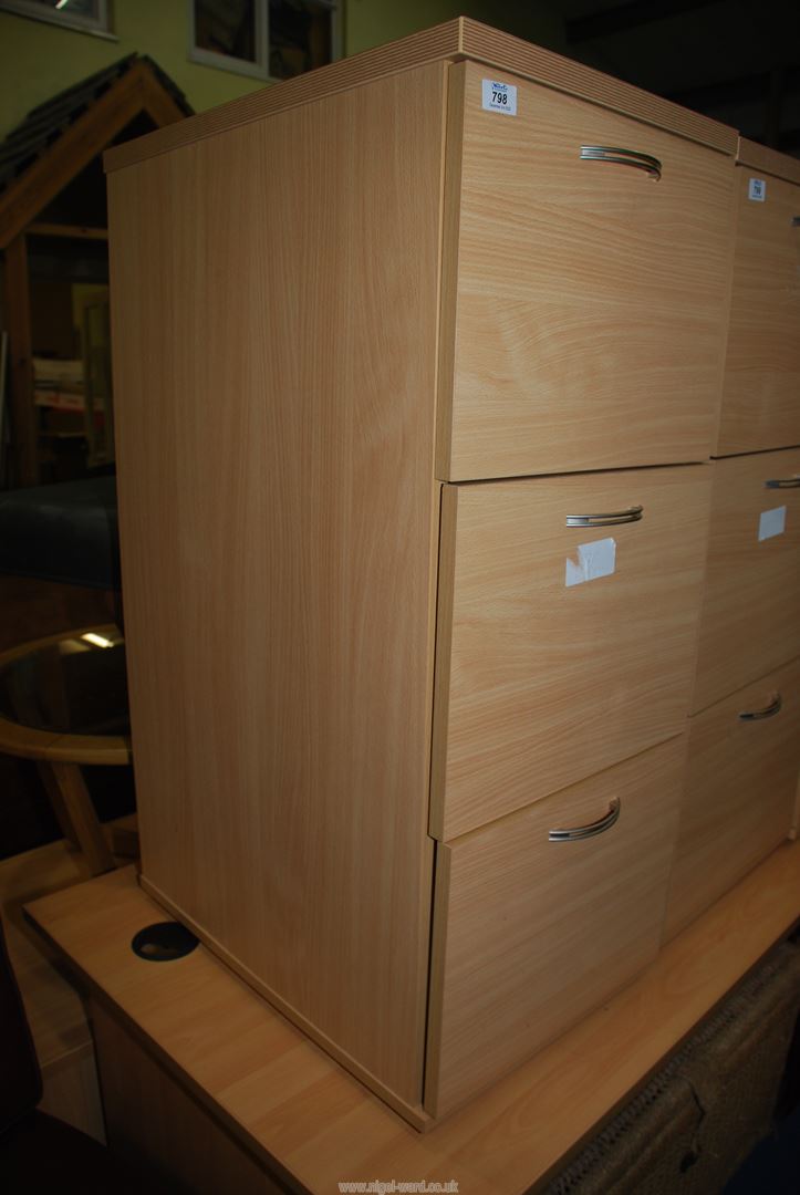 A 3 drawer wooden filing cabinet.