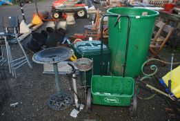 A plastic bird bath, hand operated pump, a Scott's seeder, green wheelie bin, a brass plant stand.
