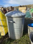 A galvanised dustbin with lid.