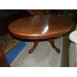 An oval Mahogany snap top centre Table standing on a heavy turned pillar with four elegant carved