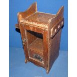An oak smokers cabinet having a glass door, drawer to base and pipe rack on the sides, 12" tall.