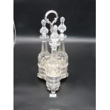 Three slender cut glass Decanters (one with chip to rim) in pierced plated stand.