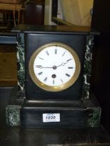 A black marble Clock with Roman numerals, (pendulum present but no key).