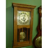 An Oak wall Clock with pendulum and key, 29" long.