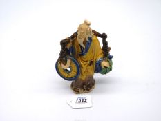 A fine vintage Chinese 'shiwan' pottery figure of an ancient bearing a yoke from which hang emblems