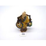 A fine vintage Chinese 'shiwan' pottery figure of an ancient bearing a yoke from which hang emblems