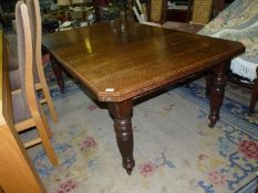 An Edwardian Oak wind-out Dining Table having turned and fluted legs, raised on brass castors,