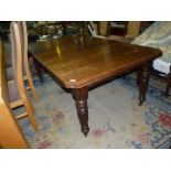 An Edwardian Oak wind-out Dining Table having turned and fluted legs, raised on brass castors,