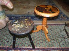 A pine occasional table with various wood grains to the top and a black wooden three legged stool