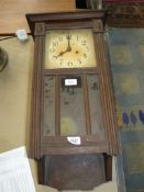 A wooden cased wall clock with pendulum.
