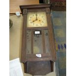 A wooden cased wall clock with pendulum.