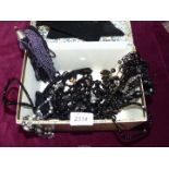 A floral jewellery box with a quantity of black bead necklaces .