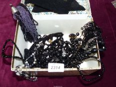 A floral jewellery box with a quantity of black bead necklaces .