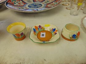 Three pieces of Clarice Cliff, Crocus pattern, pot has slight hairlines and tea cup some damage,