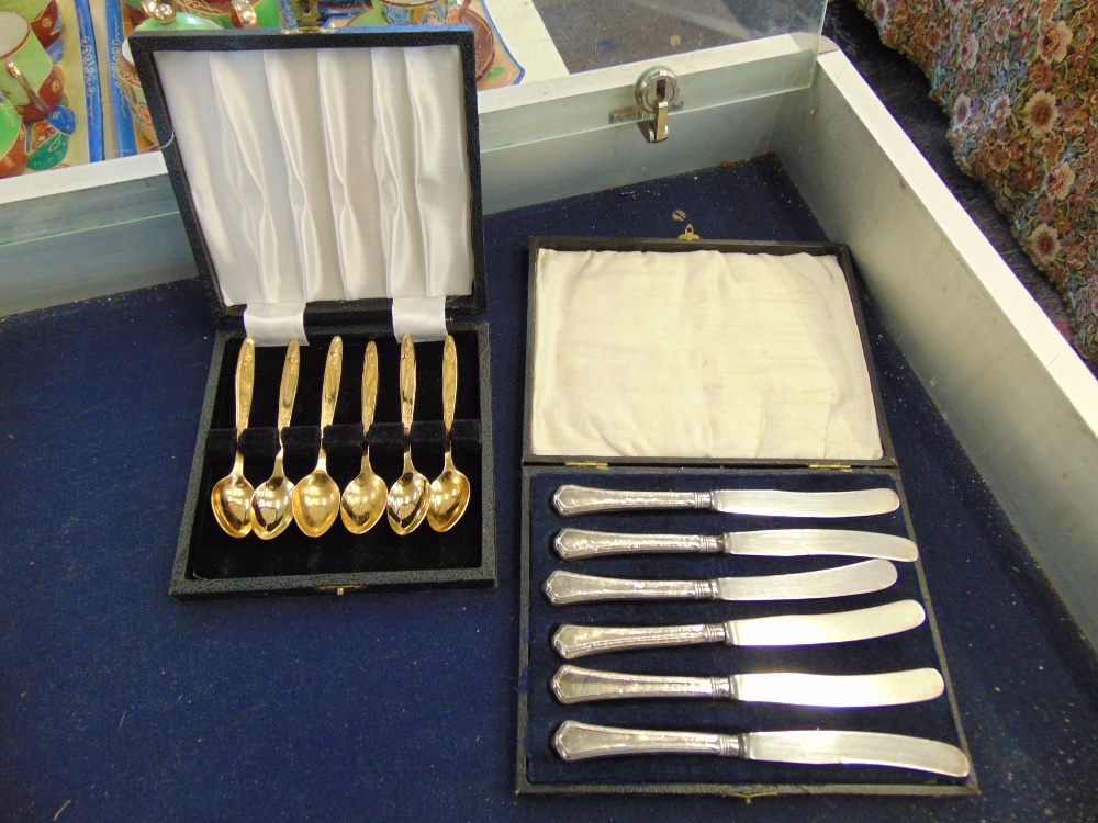 A boxed set of six Silver knives and a boxed gold plated teaspoons