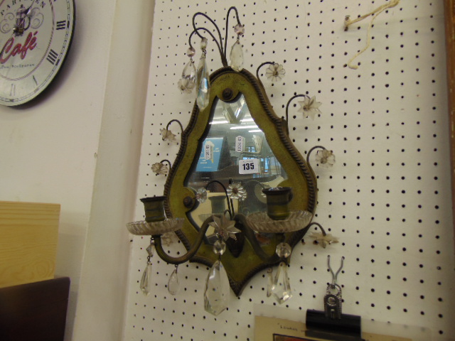 A small wall mirror with candlearbra