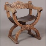A carved oak director's chair, with leather seat base and central crest to the back.