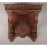 A large carved oak wall shelf, with crest to the underside and floral and foliate border. Height:
