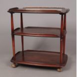 An Ercol stained beech and elm three tier serving trolley, with turned, tapered pillars, raised on