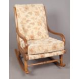 An Ercol style curved rocking chair, with scrolled arms in a light finish. Seat has light brown