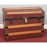 A large wooden slat domed trunk. Comprising of two carry handles and metal brackets. H: 51cm, W: