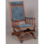 A hardwood American Rocking Chair, with blue upholstered seat and back and spindle supported arms.