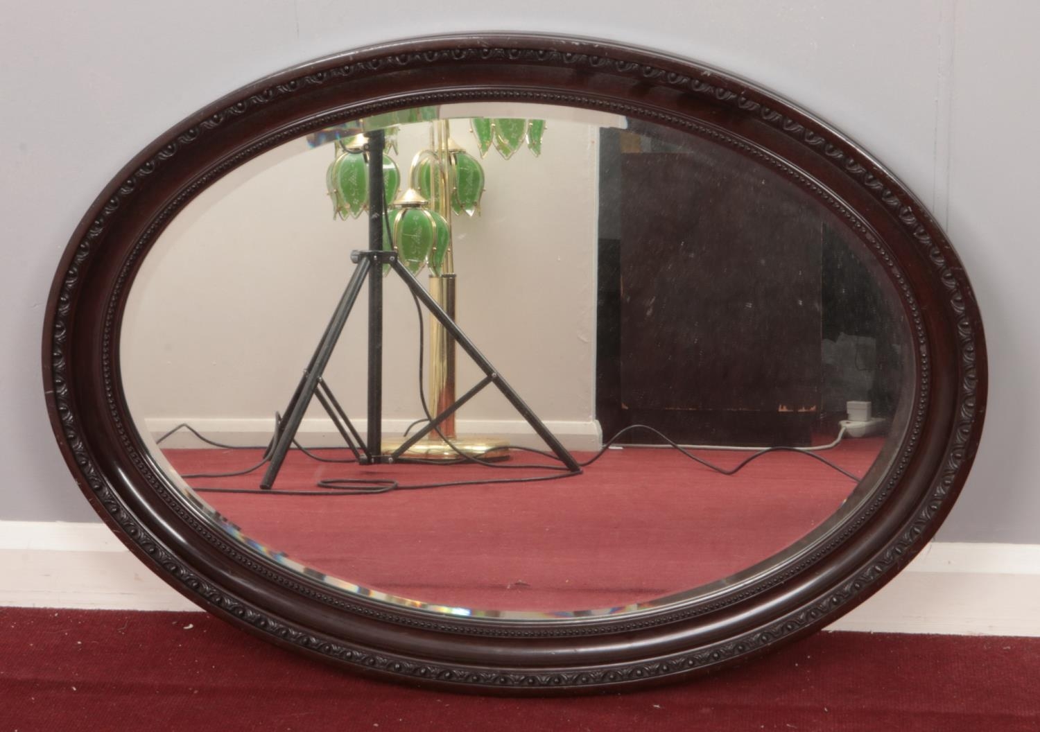 A mahogany framed, bevel edged oval mirror with beaded rim decoration.