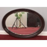 A mahogany framed, bevel edged oval mirror with beaded rim decoration.