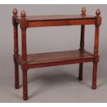 A mahogany two tier side table with removable lower shelf and turned supports. Four finials to the
