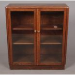 An oak three tier glass bookcase with hinged doors. Height: 104cm, Width: 91cm, Depth: 32cm. Some