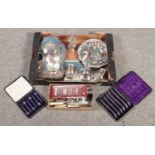 A box of silver plated items. Includes candlesticks, trays, cruets, cased knives and demitasse