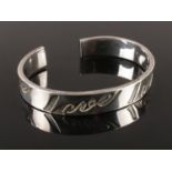 A silver bangle, embossed with 'Love'. Stamped 925. Total weight: 26.50g.