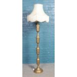 A large brass standard lamp with pierced decoration, together with frilled cream shade. Total