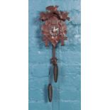 A black forest style cuckoo clock, with foliate decoration and bird to the top.