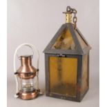 A cast iron lantern with decorative yellow glass panels, alongside a reproduction ships lantern.