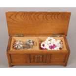 A small oak musical jewellery box, containing silver charms, brooches and cultured fresh water