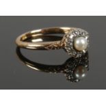 An 18ct Gold ring, set with central pearl surrounded by 9 small diamonds (1/32ct) on scrolled