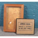 An oak glazed wall cabinet along with a framed advertising poster for Jones Bros.