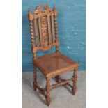A carved oak hall chair with bergère seat and floral decoration.