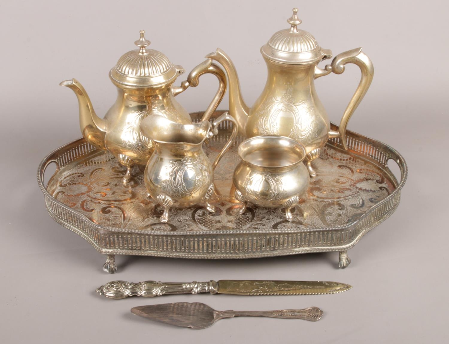 A four piece EPNS tea set with tray, cake knife and server. To include tea pot, coffee pot, sugar