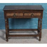 A mahogany side table with two drawers, brass handles and carved floral decoration.